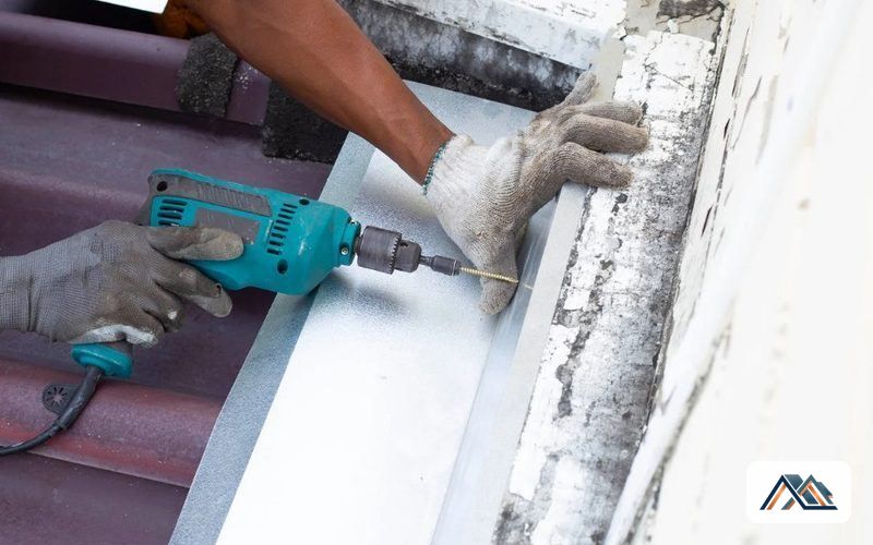 Fijación de la chapa del canalón al muro con atornillador durante la reparación