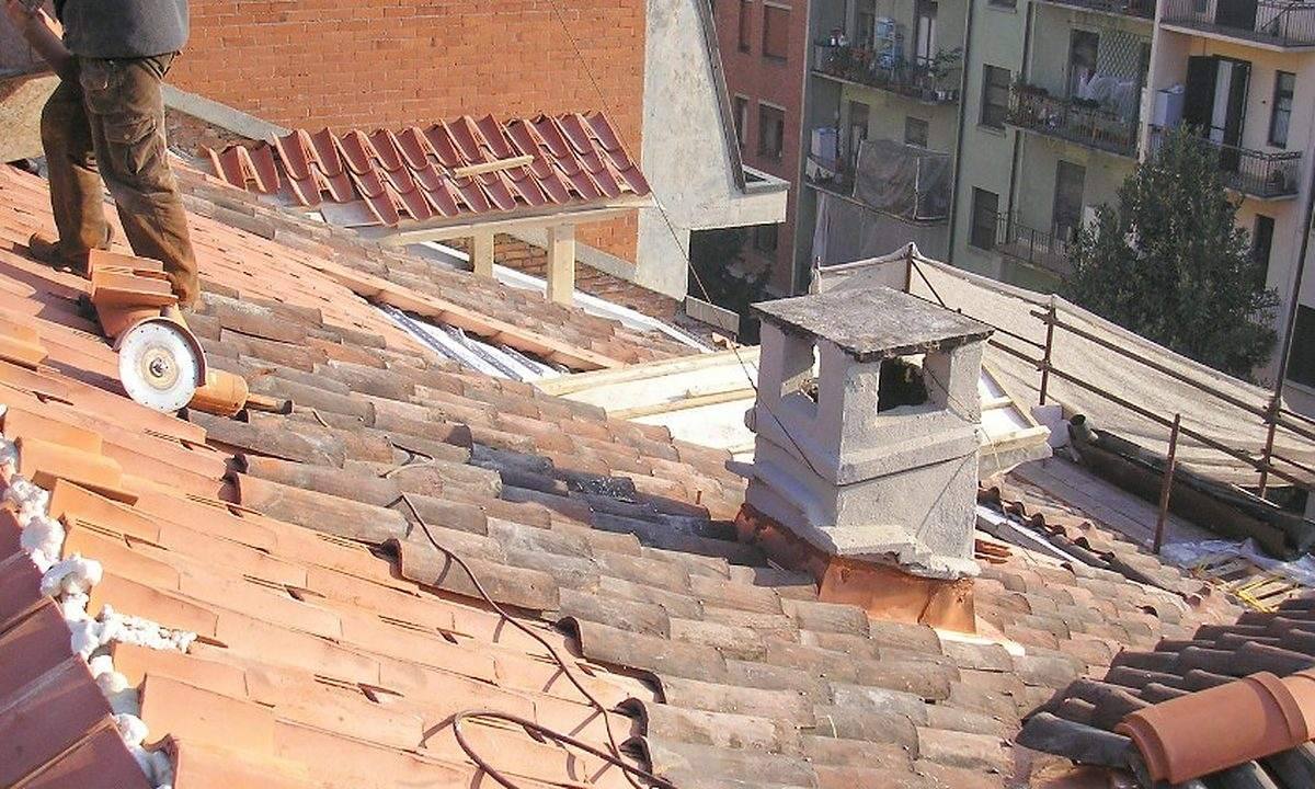 Operario retejando una cubierta junto a la chimenea de una vivienda de Lugo