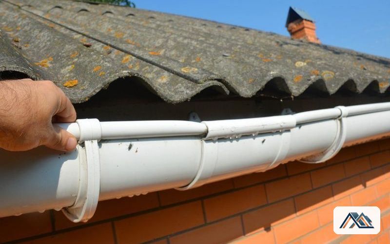 Fibrocemento con amianto en cubierta Placa ondulada de fibrocemento con líquenes y canalón de PVC en el alero de una edificación