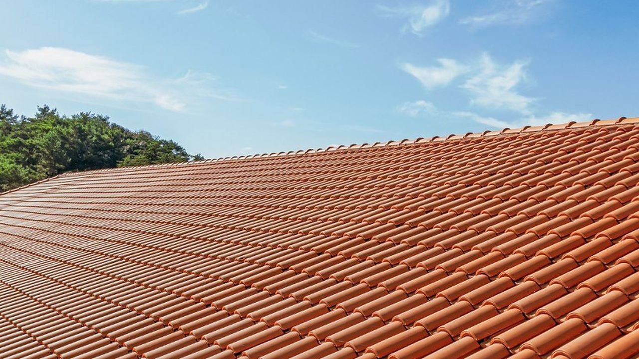 Cubierta de teja curva del país recién reparada bajo cielo despejado en Lugo