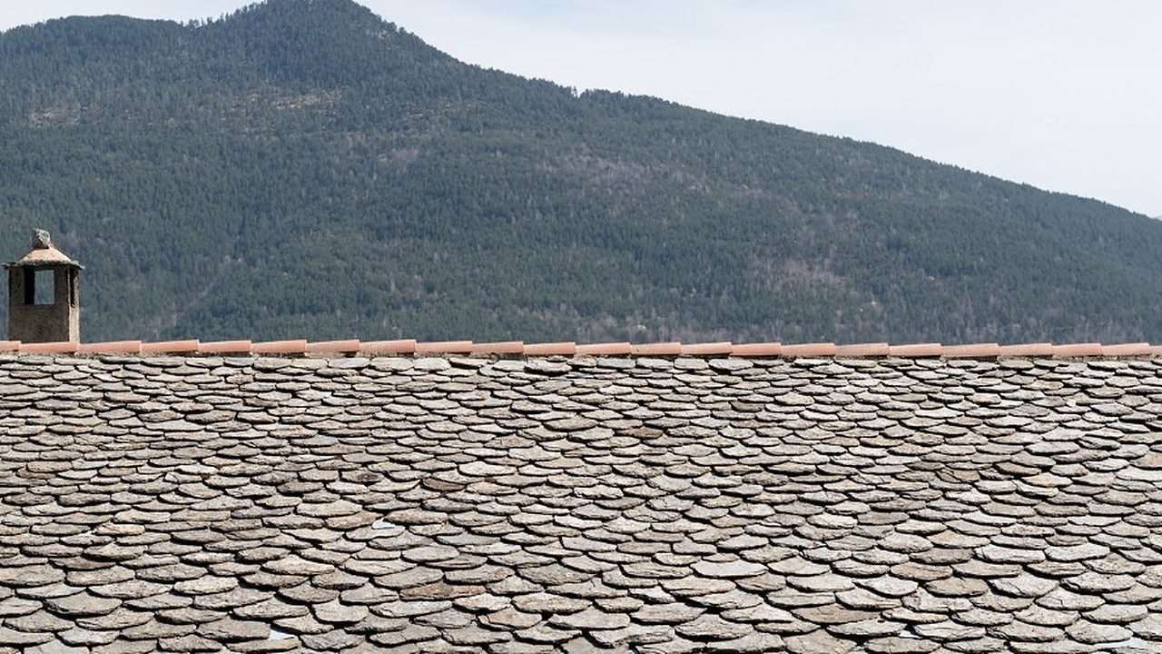 Cubierta de losa de piedra de una vivienda rural con el monte al fondo en la provincia de Lugo